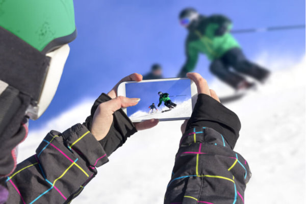Person filming skiier on their mobile phone Person filming skiier on their mobile phone