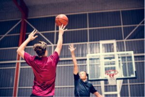 Two teenage students playing basketball indoors
